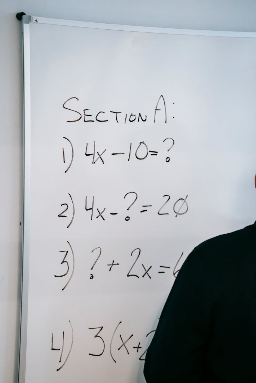 A whiteboard displaying math equations and partial silhouette of a person writing.