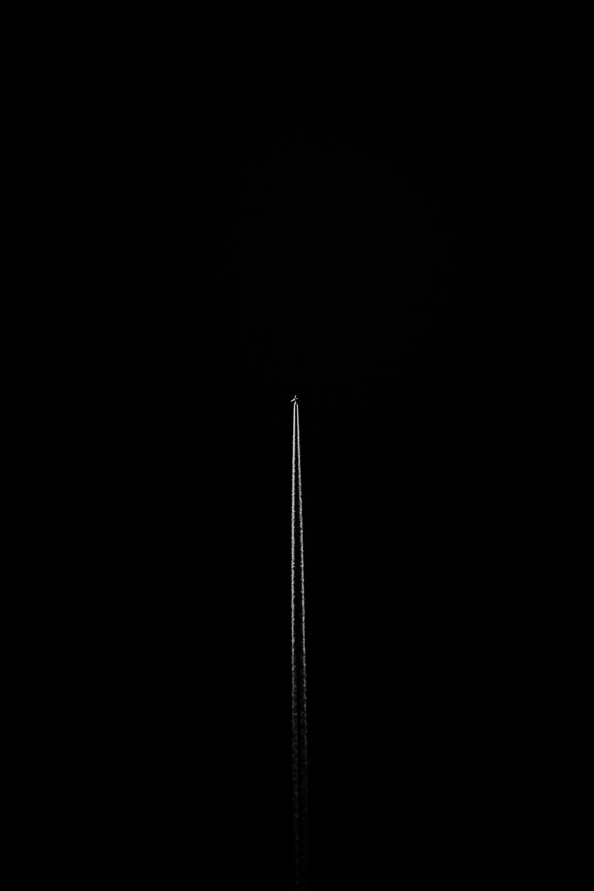 A striking capture of an airplane's contrail in a monochrome black setting, showcasing minimalism and contrast.
